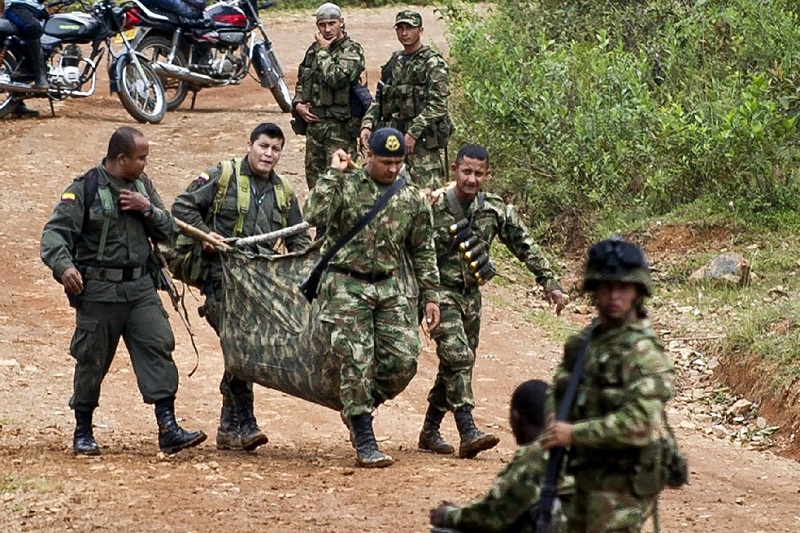 Colombian soldiers carry equipment of one of ten soldiers killed by the Revolutionary Armed Forces of Colombia (FARC) guerrillas, in the rural area of Buenos Aires, department of Cauca, Colombia, on April 15, 2015. Colombian President Juan Manuel Santos ordered the military to resume air strikes on the leftist FARC guerrillas after they allegedly killed 10 soldiers in an attack. AFP PHOTO / LUIS ROBAYO