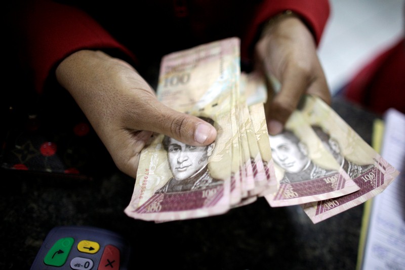 Imagen de archivo de una mujer contando bolívares en una tienda de artíulos electrónicos en La Guaira, Venezuela, ene 12 2010. Venezuela podría lanzar un nuevo sistema cambiario con dos cotizaciones al final del año, dijo el vicepresidente del área económica, Rafael Ramírez, a un diario local el lunes, con el objetivo de simplificar el actual modelo que opera dentro de un estricto control gubernamental. REUTERS/Jorge Silva