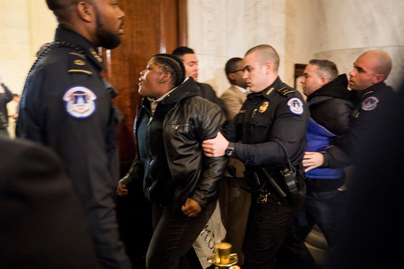 Guardias alejan los manifestantes de la sala donde se desarrolla la audiencia del senador republicano por Alabama, Jeff Sessions, para aceptar su cargo como fiscal general en la Oficina administrativa federal en Washington.