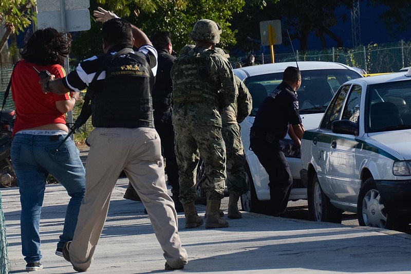 Policemen take cover during a shooting after another shooting against the building of the Quintana Roo State Prosecution, in Cancun, Mexico, on January 17, 2017. The shooting happened as Mexican authorities investigate whether a feud over local drug sales was behind a nightclub shooting that killed three foreigners and two Mexicans at a popular beach resort. Monday's shooting at the Blue Parrot club during the BPM electronic music festival rocked Playa del Carmen, a usually peaceful Caribbean seaside town. / AFP PHOTO / STR