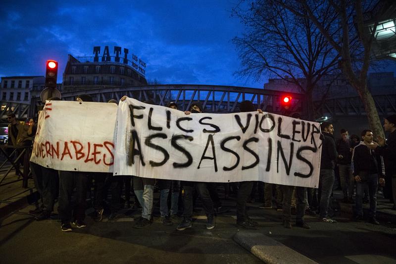 Varias personas sostienen una pancarta en la que se puede leer 'Policías, violadores, asesinos' durante una manifestación en solidaridad con Théo y contra la violencia policial en París, Francia. EFE
