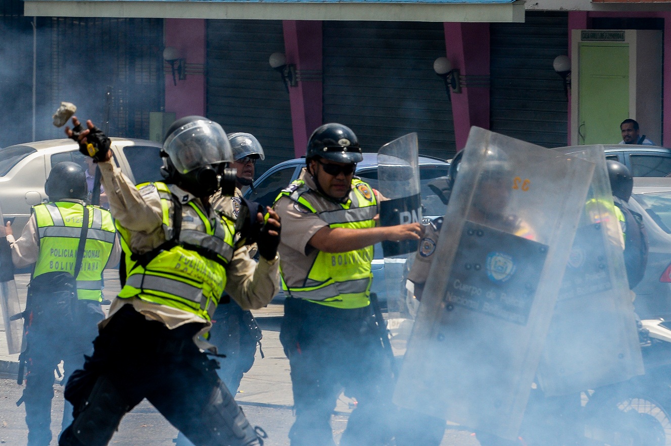 Riot police and opposition activists clash in Caracas on April 10, 2017. Venezuela's political crisis intensified last week when the Supreme Court issued rulings curbing the powers of the opposition-controlled legislature. The court reversed the rulings days later, but the opposition intensified its protests from that moment. / AFP PHOTO / FEDERICO PARRA