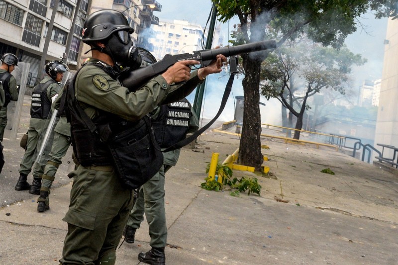 Venezuelan National Guard personnel in riot gear fire tear gas grenades at opposition activists in Caracas on April 10, 2017. Venezuela's political crisis intensified last week when the Supreme Court issued rulings curbing the powers of the opposition-controlled legislature. The court reversed the rulings days later, but the opposition intensified its protests from that moment. / AFP PHOTO / FEDERICO PARRA