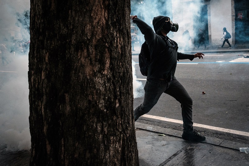 A protester throws back a tear-gas canister against military police officers during the nationwide strike called by unions opposing austerity reforms in Rio de Janeiro, Brazil, on April 28, 2017. Major transportation networks schools and banks were partially shut down across much of Brazil on Friday in what protesters called a general strike against austerity reforms in Latin America's biggest country. / AFP PHOTO / YASUYOSHI CHIBA