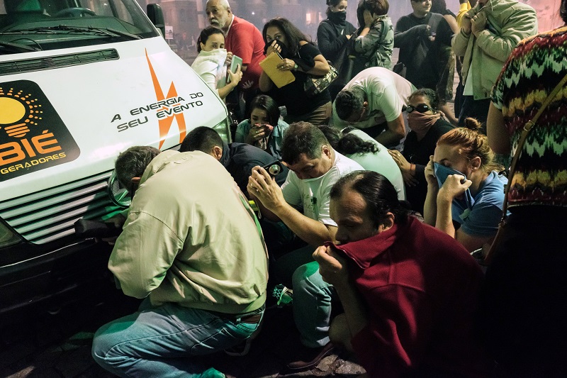 Protesters take cover behind a van from the tear gas fired by the military police during the nationwide strike called by unions opposing austerity reforms in Rio de Janeiro, Brazil, on April 28, 2017. Major transportation networks schools and banks were partially shut down across much of Brazil on Friday in what protesters called a general strike against austerity reforms in Latin America's biggest country. / AFP PHOTO / YASUYOSHI CHIBA