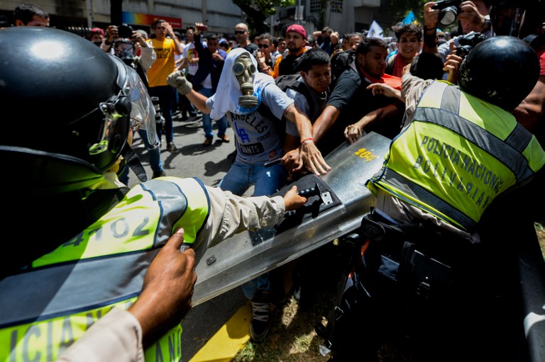 Opposition activists scuffle with riot police during a protest against President Nicolas Maduro's government in Caracas on April 4, 2017.  Activists clashed with police in Venezuela Tuesday as the opposition mobilized against moves to tighten President Nicolas Maduro's grip on power. Protesters hurled stones at riot police who fired tear gas as they blocked the demonstrators from advancing through central Caracas, where pro-government activists were also planning to march. / AFP PHOTO / FEDERICO PARRA