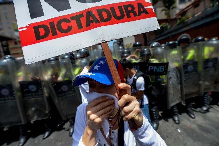 Opposition activists protest against President Nicolas Maduro's government in Caracas on April 4, 2017.  Activists clashed with police in Venezuela Tuesday as the opposition mobilized against moves to tighten President Nicolas Maduro's grip on power. Protesters hurled stones at riot police who fired tear gas as they blocked the demonstrators from advancing through central Caracas, where pro-government activists were also planning to march. / AFP PHOTO / FEDERICO PARRA