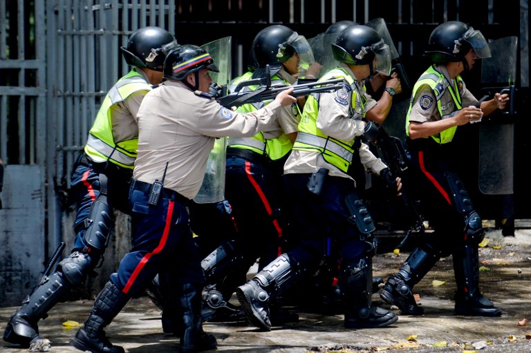 Riot police charge on demonstrators protesting against President Nicolas Maduro's government in Caracas on April 4, 2017.  Activists clashed with police in Venezuela Tuesday as the opposition mobilized against moves to tighten President Nicolas Maduro's grip on power. Protesters hurled stones at riot police who fired tear gas as they blocked the demonstrators from advancing through central Caracas, where pro-government activists were also planning to march. / AFP PHOTO / FEDERICO PARRA