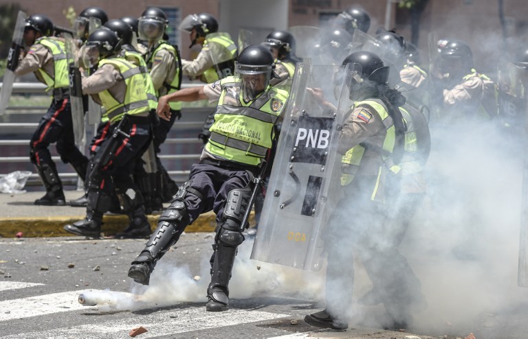 Bolivarian police agents kick back a tear gas grenade, during clashes with Nicolas Maduro's government opposition activists in Caracas on April 4, 2017. Protesters clashed with police in Venezuela Tuesday as the opposition mobilized against moves to tighten President Nicolas Maduro's grip on power. Protesters hurled stones at riot police who fired tear gas as they blocked the demonstrators from advancing through central Caracas, where pro-government activists were also planning to march.  / AFP PHOTO / JUAN BARRETO