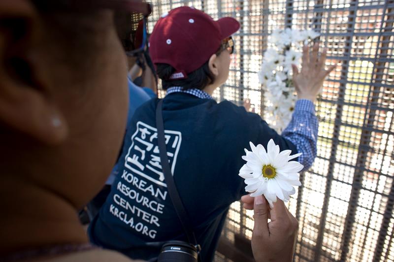 Un miembro de un colectivo de activistas denominado "Caravan Against Fear" (caravana contra el miedo), coloca un ramo de flores en el muro fronterizo entre Estados Unidos y México, durante una visita al Parque de la Amistad hoy, domingo 16 de abril de 2017, en San Diego, California. EFE