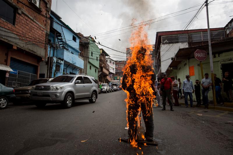 n grupo de personas participa en la quema de judas con un muñeco al que se le colocaron fotografías de varios personajes internacionales hoy, domingo 16 de abril de 2017, en el marco de la celebración del Domingo de Resurrección de la Semana Santa en Caracas (Venezuela). EFE