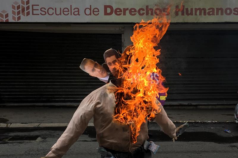 Fotografía de un muñeco quemándose con fotografías del defensor del pueblo de Venezuela, Tarek Wiliam Saab, y el presidente de Venezuela, Nicolás Maduro, durante la "Quema de Judas" hoy, domingo 16 de abril de 2017, en el marco de la Semana Santa en Caracas (Venezuela). EFE