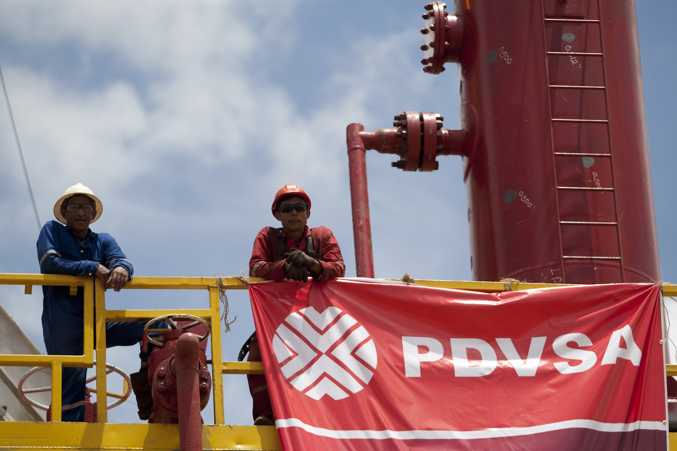 Workers stand in front of a drilling rig at an oil well operated by Venezuela's state oil company PDVSA in Morichal July 28, 2011.  Venezuela received an enviable honor last month: OPEC said it is sitting on the biggest reserves of crude oil in the world -- even more than Saudi Arabia.  But the Venezuelan oil industry is also sitting atop a well of trouble.  Picture taken July 28, 2011.  To match Special Report VENEZUELA/PDVSA  REUTERS/Carlos Garcia Rawlins (VENEZUELA - Tags: ENERGY POLITICS BUSINESS)