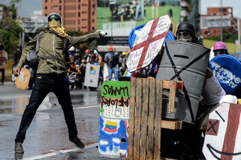 Opposition demonstrators clash with riot police in Caracas, on May 24, 2017. Venezuela's President Nicolas Maduro formally launched moves to rewrite the constitution on Tuesday, defying opponents who accuse him of clinging to power in a political crisis that has prompted deadly unrest. / AFP PHOTO / FEDERICO PARRA