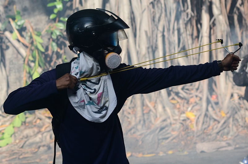 An opposition demonstrator clashes with riot police in Caracas, on May 24, 2017. Venezuela's President Nicolas Maduro formally launched moves to rewrite the constitution on Tuesday, defying opponents who accuse him of clinging to power in a political crisis that has prompted deadly unrest. / AFP PHOTO / FEDERICO PARRA