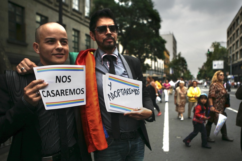 A gay couple hold up signs that read in Spanish "We will marry and we will adopt" during a demonstration outside the Supreme Court in Mexico City, Monday, Aug. 16, 2010. Mexico's Supreme Court voted Monday to uphold a Mexico City law allowing adoptions by same-sex couples. The justices voted 9-2 against challenges presented by federal prosecutors and others who had argued the law fails to protect adoptive children against possible ill effects or discrimination, or to guarantee their rights to a traditional family. (AP Photo/Miguel Tovar)