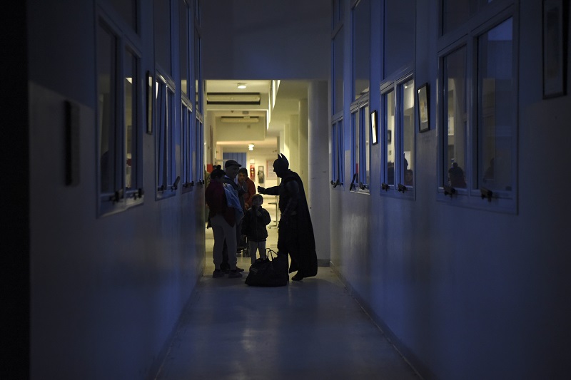 Argentine Batman, greets a family in a corridor of the 'Sor Maria Ludovica' children's Hospital in La Plata, 60 kilometres south of Buenos Aires, on June 2, 2017. The Argentine Batman has made La Plata children's hospital a target of laughter and treats against pain. / AFP PHOTO / Eitan ABRAMOVICH