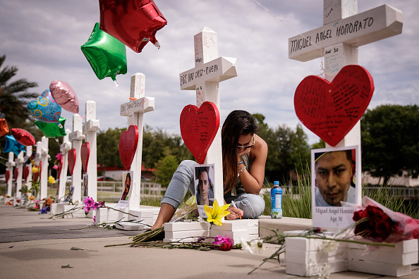 ORLANDO, FL - JUNE 17: A woman writes a note on a cross for Eric Ivan Ortiz-Rivera at a memorial with wooden crosses for each of the 49 victims of the Pulse Nightclub, next to the Orlando Regional Medical Center, June 17, 2016 in Orlando, Florida. The shooting at Pulse Nightclub, which killed 49 people and injured 53, is the worst mass-shooting event in American history. (Photo by Drew Angerer/Getty Images)