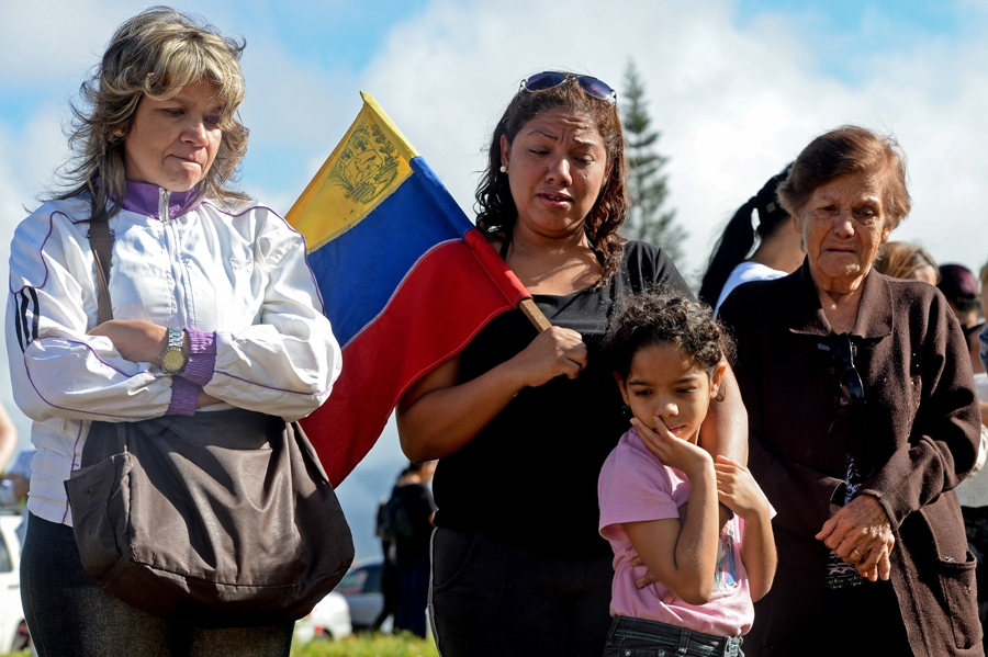 Former elite police officer Oscar Perez's supporters mourn next to his gravesite at a cemetery in Caracas on January 21, 2018. Perez's body was burried by the government early in the morning on January 21 against his family will. He was Venezuela's most wanted man since June when he flew a stolen police helicopter over Caracas dropping grenades on the Supreme Court and opening fire on the Interior Ministry, had gone on social media while the operation was under way on January 16 to say he and his group wanted to surrender but were under unrelenting sniper fire. That has raised questions about the government's account that the seven dissidents killed had opened fire on police who had gone to arrest them. / AFP PHOTO / Federico PARRA