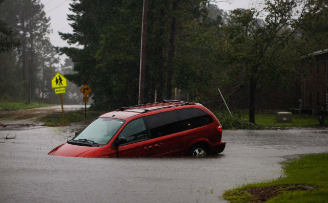 An abandoned mini van sits on a flooded road near New Bern, NC on September 14, 2018 during Hurricane Florence.  Florence smashed into the US East Coast Friday with howling winds, torrential rains and life-threatening storm surges as emergency crews scrambled to rescue hundreds of people stranded in their homes by flood waters. Forecasters warned of catastrophic flooding and other mayhem from the monster storm, which is only Category 1 but physically sprawling and dangerous. / AFP PHOTO / Logan Cyrus